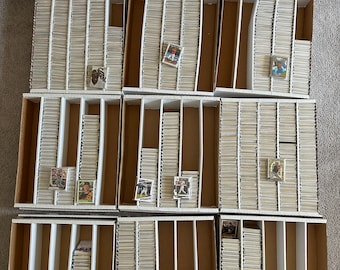 May include: A white cardboard box with multiple compartments filled with baseball cards. The box is open and the cards are visible. The cards are in rows and columns, and they are all different.