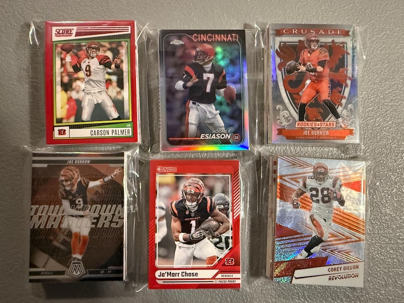 May include: A collection of six football trading cards, each encased in a protective sleeve. The cards feature images of players in action, with team logos and player names visible. The cards are in various designs and colors.
