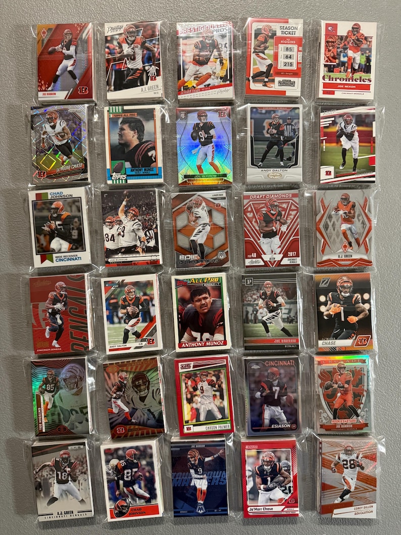 May include: A collection of football trading cards featuring players in orange and black uniforms. The cards are in protective sleeves and showcase various action shots and player portraits. Some cards have text like "Chad Johnson" and "Cincinnati".