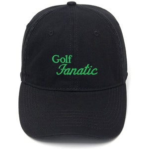 May include: Black baseball cap with green embroidered text that reads "Golf Fanatic".