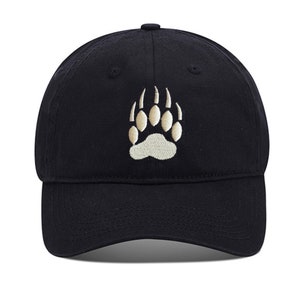 May include: A black baseball cap with a white embroidered bear paw print.
