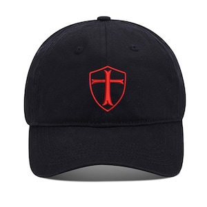 May include: A black baseball cap with a red embroidered shield featuring a cross.