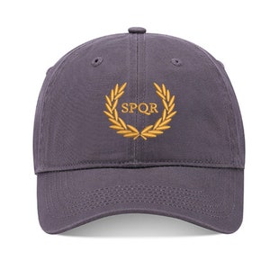 May include: A dark gray baseball cap with an embroidered gold laurel wreath and the text "SPQR" in the center.