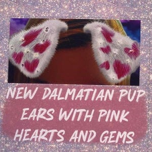 May include: White, fluffy Dalmatian pup ears with pink heart accents and sparkling gems. The text on the image reads "NEW DALMATIAN PUP EARS WITH PINK HEARTS AND GEMS". These ears are a fun accessory.