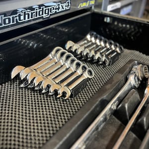 May include: A collection of shiny, silver wrenches neatly arranged in a toolbox drawer. The wrenches are of various sizes and styles, including open-end and ratcheting box wrenches. The toolbox has the text "Northridge4x4" on the top.