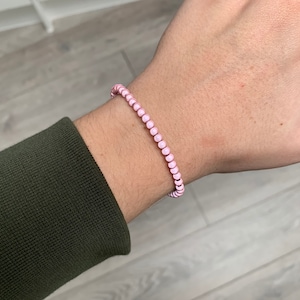 Puede incluir: Un brazalete de cuentas rosadas en la muñeca.