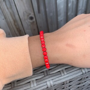 May include: A red beaded bracelet with round beads.