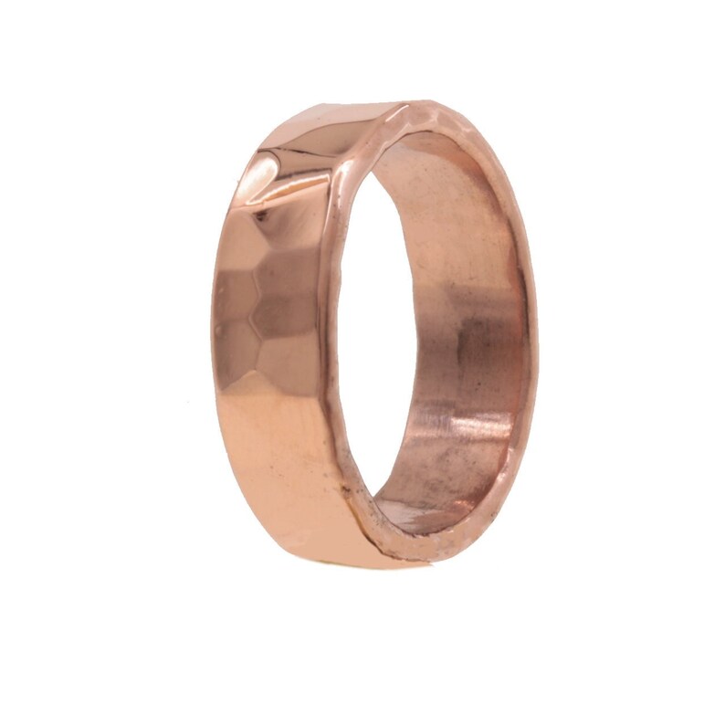 May include: A hammered rose gold ring with a wide band.