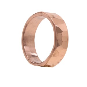 May include: A hammered rose gold ring with a wide band.