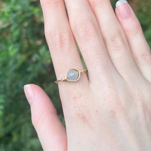 May include: A gold wire wrapped ring with a clear, round gemstone.