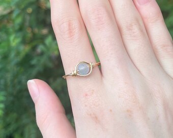 Puede incluir: Un anillo de alambre dorado con una piedra redonda transparente.