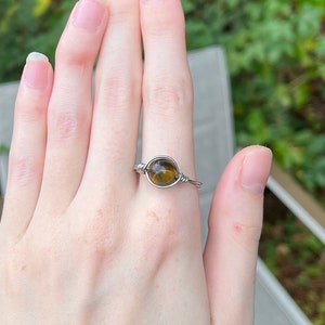 May include: A silver wire wrapped ring with a brown tiger's eye gemstone.