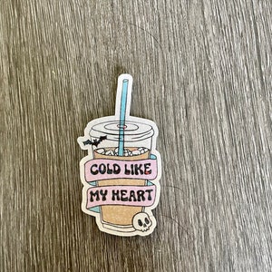 Pu&ograve; includere: Un adesivo con un cartone animato di un bicchiere di caff&egrave; freddo con una cannuccia, un pipistrello e il testo "Cold Like My Heart".