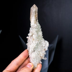 以下が含まれることがあります： 先が尖った透明なトップを持つ、大きな透明な水晶のクラスター。水晶は、より小さな白い水晶で囲まれています。
