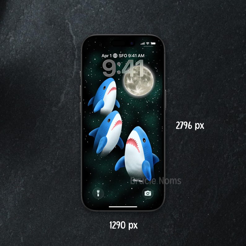 May include: A smartphone displays a whimsical wallpaper featuring three cartoon sharks swimming in a starry night sky with a full moon. The time is 9:41 AM, April 1st, SFO.