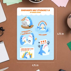 May include: A sticker sheet featuring shark illustrations with text such as "CORPORATE SLAVE" and "TRAUMA BONDED WITH MY WORK BESTIES." The sheet is labeled "CORPORATE HAJ STICKERS 1.0." The sticker sheet measures approximately 12.07 cm x 17.15 cm.