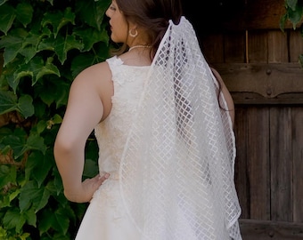 Impresionante velo de novia con lentejuelas y borde de cinta con patrón de diamantes. Disponible en punta de dedo, pantorrilla, vals, charco, capilla, catedral y real.
