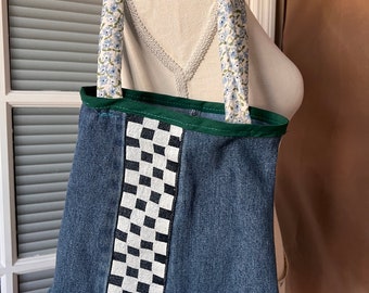 May include: A blue denim tote bag with a black and white checkered stripe down the side. The bag has green trim and floral fabric straps.