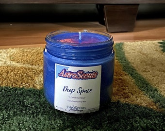 May include: A blue soy candle with a glittery finish and a label that reads "Astro Scents Deep Space "A Candle for Sleep" 100% Natural Soy Wax AstroScents".