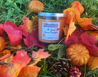 May include: A glass candle jar with a silver lid. The candle is a light orange color and has a label that reads "AstroScents The Great Spiced Pumpkin 100% Soy Wax Hand Poured in the USA AstroScents". The candle is surrounded by fall leaves and decorative pumpkins.