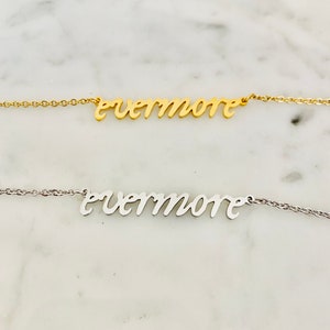 May include: Two necklaces with the word "evermore" in a cursive font. One necklace is gold-colored, and the other is silver-colored. Both necklaces are on a delicate chain.