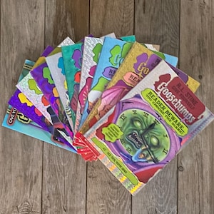 May include: A stack of Goosebumps books with colourful covers featuring spooky characters and scenes. The top book is titled "Reader Beware" and features a green monster with a clock face.