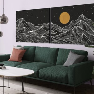 May include: A green velvet sofa with two pillows sits in front of a black and white abstract art print depicting mountains and a yellow moon. The print is in two parts, and the sofa is in a modern living room setting.