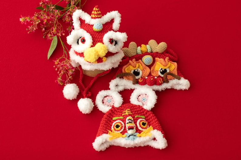 May include: Three red, white and yellow crocheted lion hats with fluffy white trim. The hats have embroidered eyes and a red and yellow lion face.