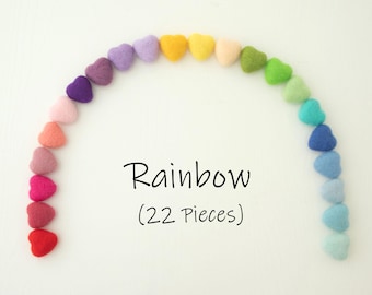 May include: A rainbow of felt hearts arranged in a semi-circle. The hearts are in shades of red, orange, yellow, green, blue, indigo, and violet. The text "Rainbow (22 Pieces)" is written below the hearts.