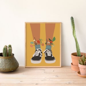 May include: A framed illustration of a pair of black trainers with flowers growing out of the tops. The background is a yellow colour.