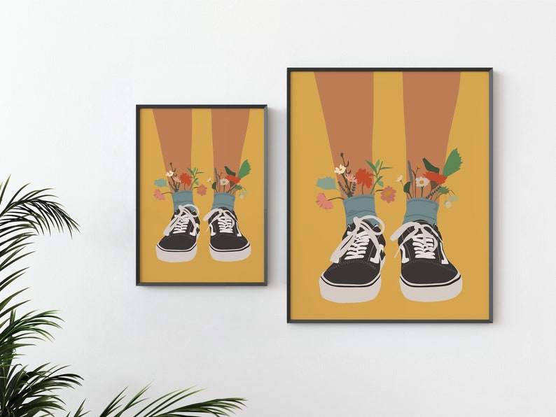 May include: A pair of black canvas trainers with white laces and a yellow background. Flowers are growing out of the top of the trainers.