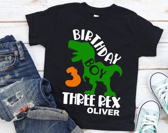 May include: Black t-shirt with a green dinosaur graphic and the text "Birthday Boy Three Rex Oliver".