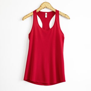 May include: A red racerback tank top with a scoop neck. The tank top is hanging on a gold hanger.