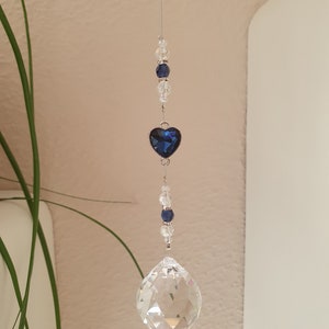 May include: A crystal suncatcher with a blue heart charm and clear crystal beads hanging from a silver string.