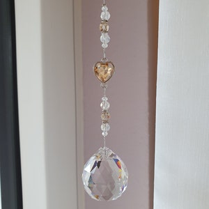 May include: A crystal suncatcher with a clear crystal ball and a gold heart charm hanging from a silver chain.