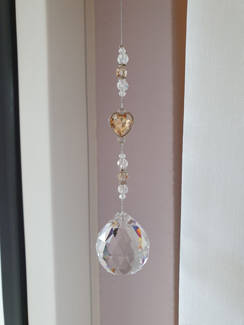 May include: A crystal suncatcher with a clear crystal ball and a gold heart charm hanging from a silver chain.