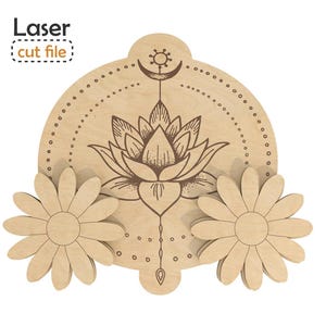 Könnte beinhalten: Eine helle Holz-Laserschnittdatei mit einer zentralen kreisförmigen Platte, die eine gravierte Lotusblume, eine Mondsichel und ein Sonnensymbol zeigt. Zwei separate, gänseblümchenförmige Holzausschnitte sind links und rechts angebracht.