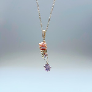 K&ouml;nnte beinhalten: Eine zarte goldene Kettenkette mit einem Anh&auml;nger aus rosa und wei&szlig;en Perlen. Der Anh&auml;nger hat eine sternf&ouml;rmige Perle mit einer kleineren Perle, die daran h&auml;ngt.