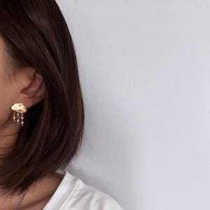 May include: Gold cloud-shaped earrings with a dangling chain of small pearls.