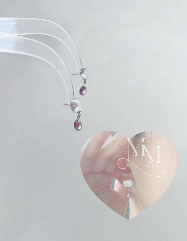 May include: A pair of silver earrings with a white pearl and a pink pearl dangling from each. The earrings are shown on a white background and in a heart-shaped frame with the text "Mimi Baroque Jewelry".