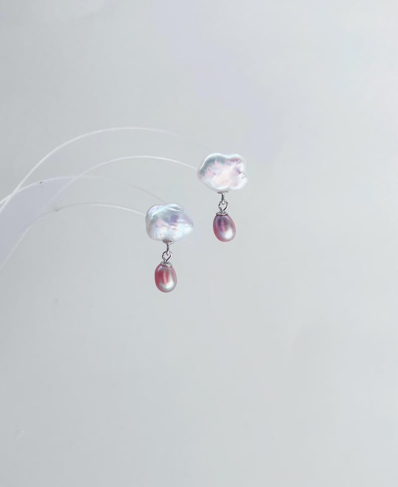 May include: A pair of silver earrings with a white baroque pearl and a pink pearl drop.