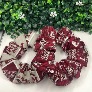 May include: Two maroon and white scrunchies with the Texas A&M logo repeated on the fabric.