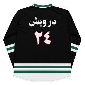 May include: Black long-sleeved jersey with white and green stripes. The back of the jersey has the text "درويش" and the number "٢٤" in white with a red outline.