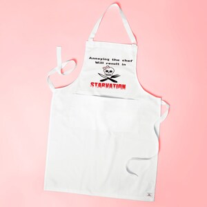 May include: White kitchen apron with a skull and crossbones design and the text "Annoying the chef will result in STARVATION".