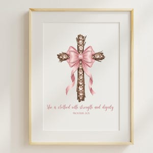 May include: Framed print of a cross crafted from twigs, embellished with sparkling gems and a pink bow. A vertical line of gems runs down the centre. The text "She is clothed with strength and dignity" is below the cross.