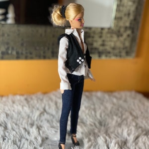 May include: A blonde doll wearing a white button-down shirt, a black vest with white buttons, dark blue jeans, and black heels.