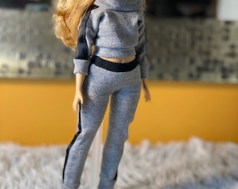 May include: A gray and black tracksuit with a black trim. The top has a mock neck and long sleeves. The pants have a straight leg and black stripes down the sides.