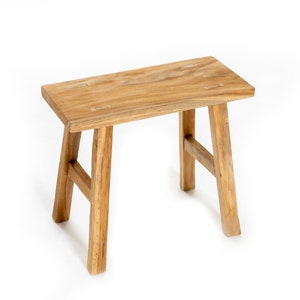 Peut inclure: Un tabouret en bois simple avec un siège rectangulaire et quatre pieds. Le tabouret est en bois naturel et a un style rustique, de ferme.
