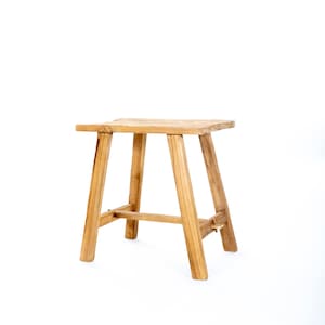 Puede incluir: Un taburete de madera simple con un asiento rectangular y cuatro patas. El taburete está hecho de madera natural y tiene un aspecto rústico.