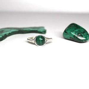 May include: A silver wire wrapped ring with a green malachite stone.